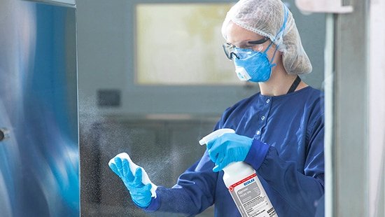 Operator spraying a transfer hatch with Klercide alcohol